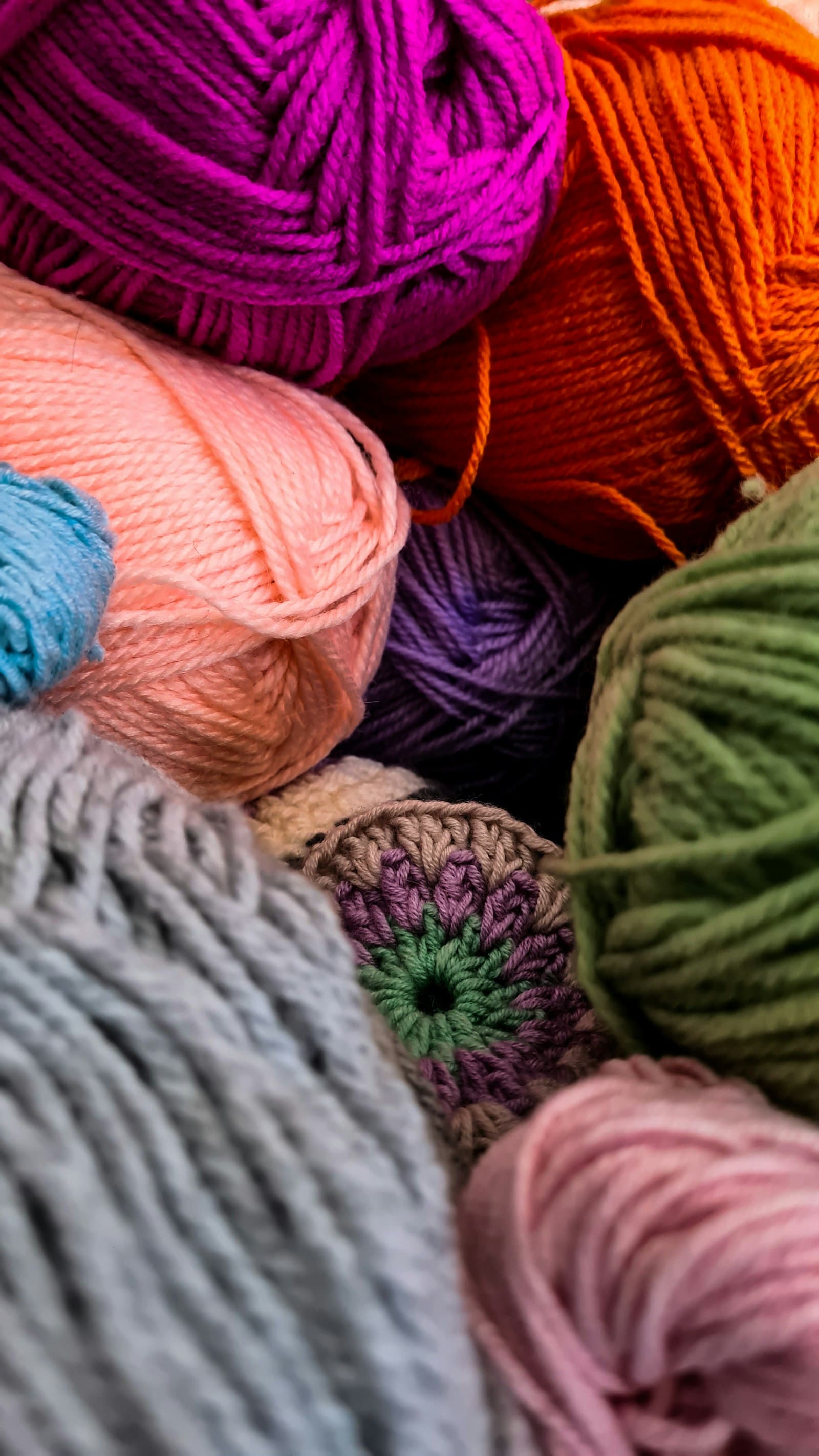 Balls of blue, orange, and green yarn stacked together
