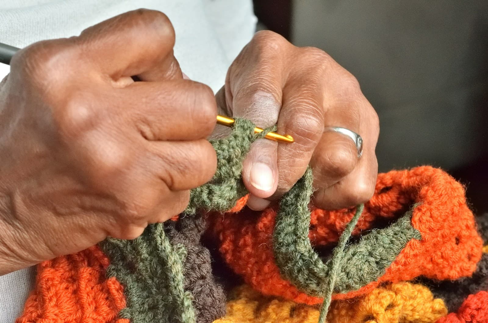 Hands holding a crochet hook working on a new crochet round
