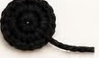 Flat black crocheted eye patch disc with a long yarn tail left for sewing onto the panda's face