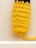 Small yellow and black crocheted Pikachu ear, folded flat with a black tip