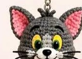 Finished gray crocheted Tom head, closed at the top after stuffing, with safety eyes and embroidered face details already added